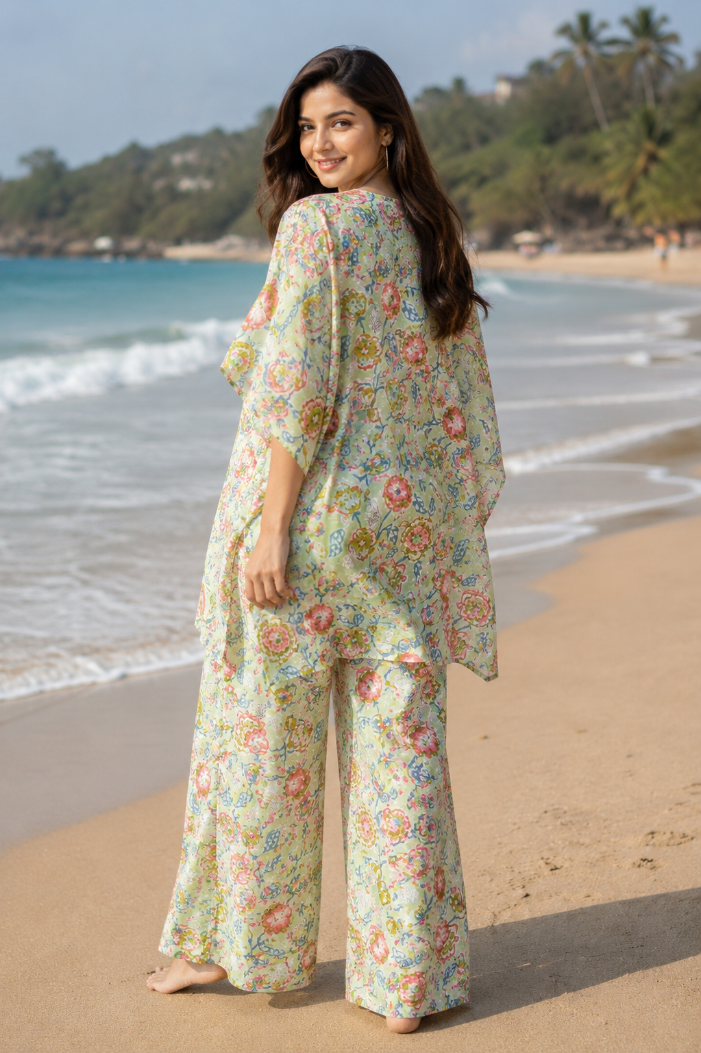 Woman wearing sage green floral kaftan co-ord set on beach - back view